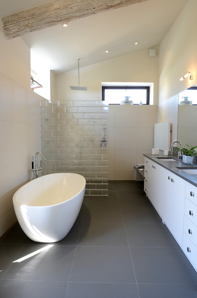 Inspiration för mellanstora moderna en-suite badrum, med släta luckor, vita skåp, ett platsbyggt badkar, en kantlös dusch, vit kakel, keramikplattor, vita väggar, klinkergolv i keramik, ett integrerad handfat, grått golv och med dusch som är öppen