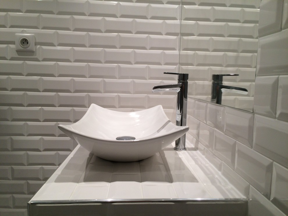 Modern inredning av ett litet badrum, med ett fristående handfat, kaklad bänkskiva, vit kakel, vita väggar och tunnelbanekakel