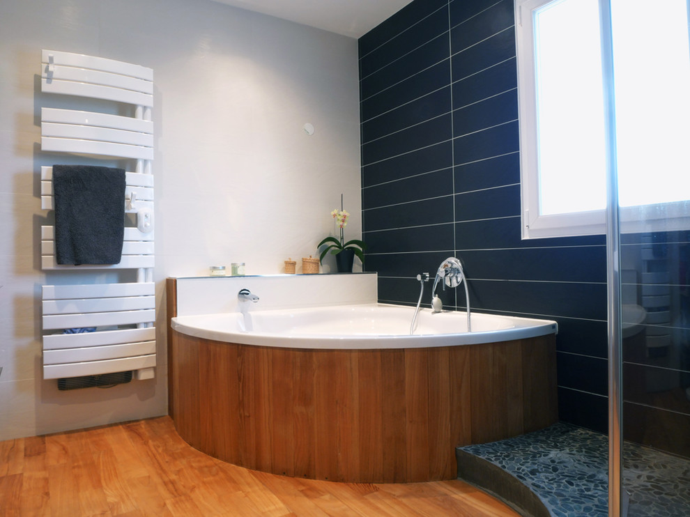 Modelo de cuarto de baño contemporáneo con bañera esquinera, ducha a ras de suelo, paredes negras y suelo de baldosas tipo guijarro
