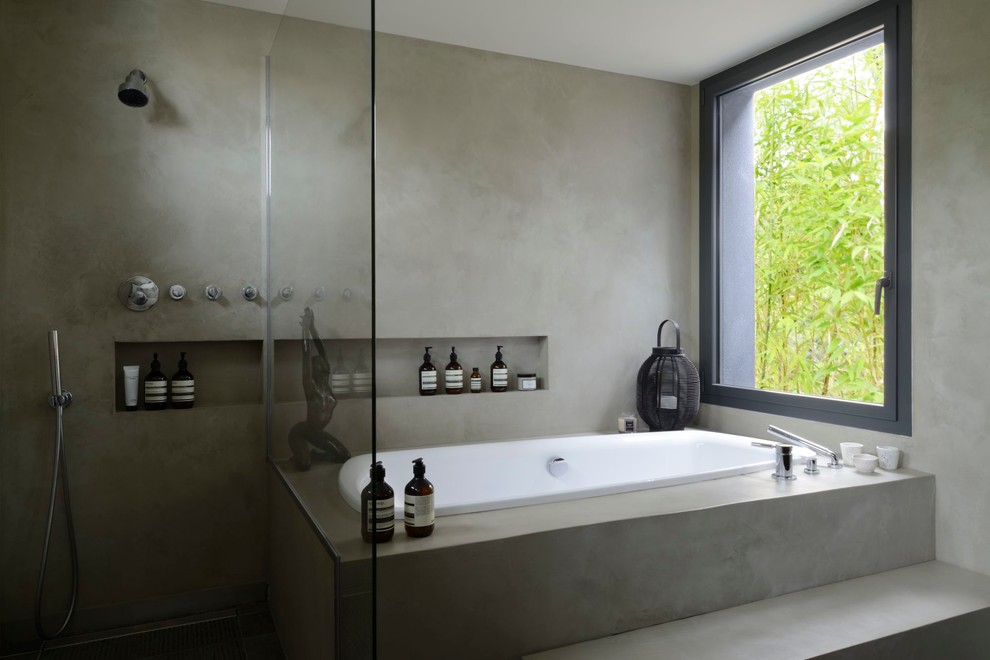 Diseño de cuarto de baño principal de estilo zen grande con armarios abiertos, bañera encastrada, ducha a ras de suelo, paredes grises, suelo de cemento y ducha abierta