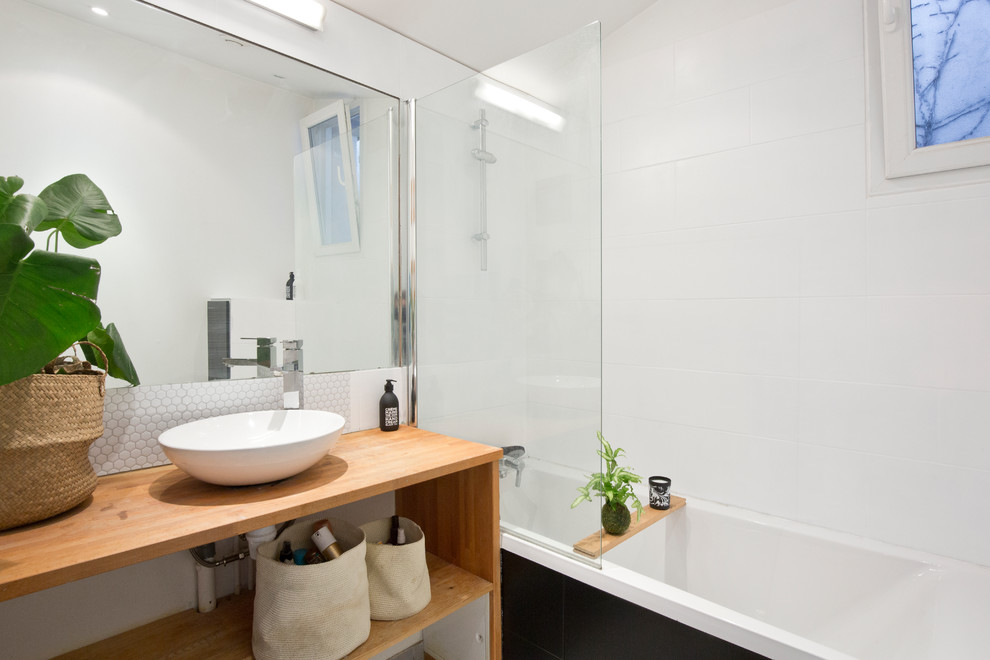 Foto på ett mellanstort tropiskt brun en-suite badrum, med öppna hyllor, skåp i mellenmörkt trä, ett platsbyggt badkar, en dusch/badkar-kombination, svart kakel, vit kakel, ett fristående handfat, cementkakel, vita väggar, träbänkskiva och med dusch som är öppen