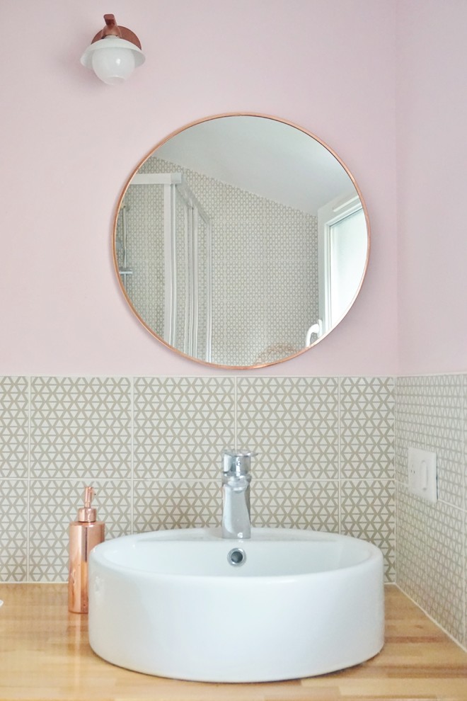 Foto på ett mellanstort funkis badrum med dusch, med öppna hyllor, vita skåp, en vägghängd toalettstol, gul kakel, cementkakel, rosa väggar, ljust trägolv, ett fristående handfat och träbänkskiva