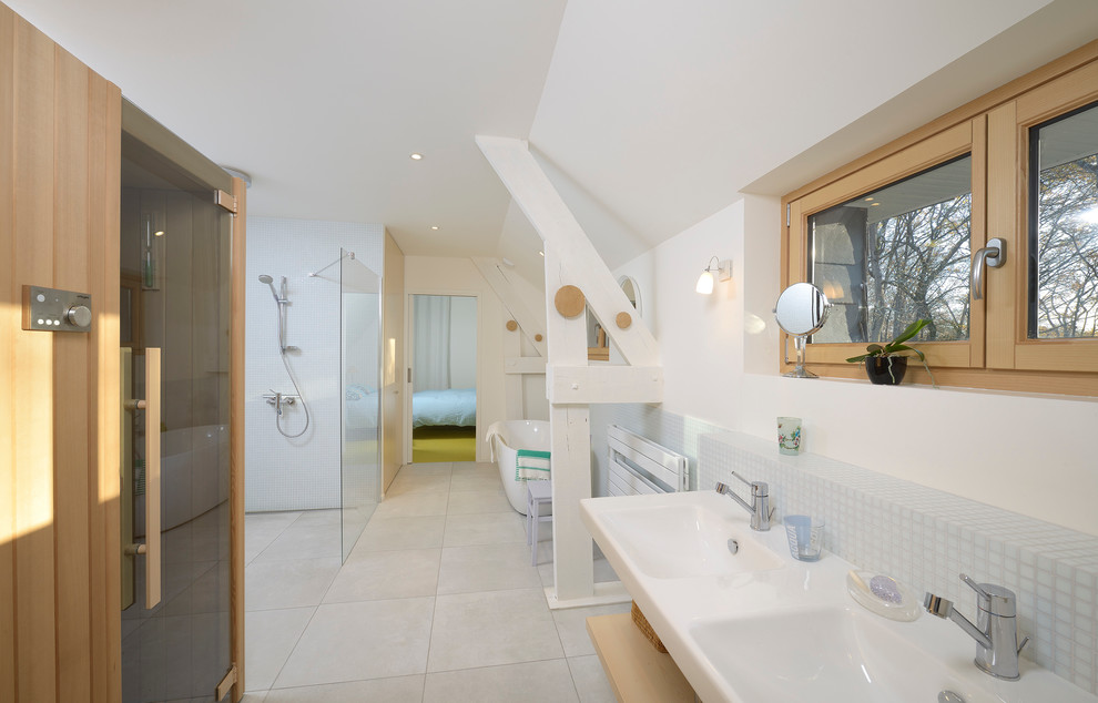 This is an example of a large contemporary bathroom in Angers with light wood cabinets, a built-in bath, a built-in shower, white walls, ceramic flooring and a console sink.