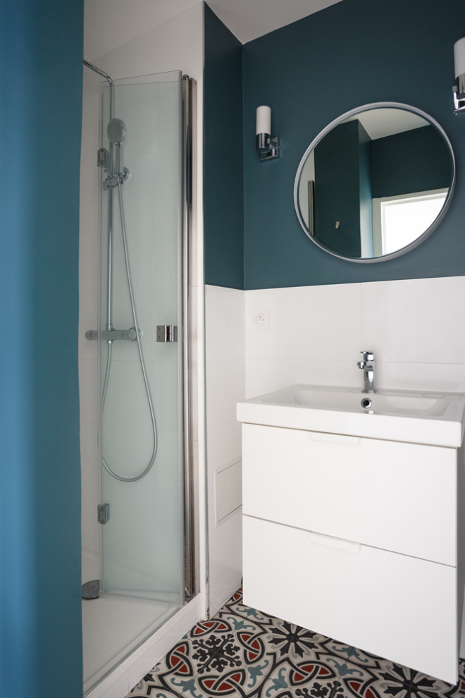 パリにあるお手頃価格の中くらいなおしゃれなバスルーム (浴槽なし) (インセット扉のキャビネット、白いキャビネット、アルコーブ型シャワー、白いタイル、磁器タイル、青い壁、セメントタイルの床、ベッセル式洗面器、人工大理石カウンター、マルチカラーの床、引戸のシャワー、白い洗面カウンター) の写真
