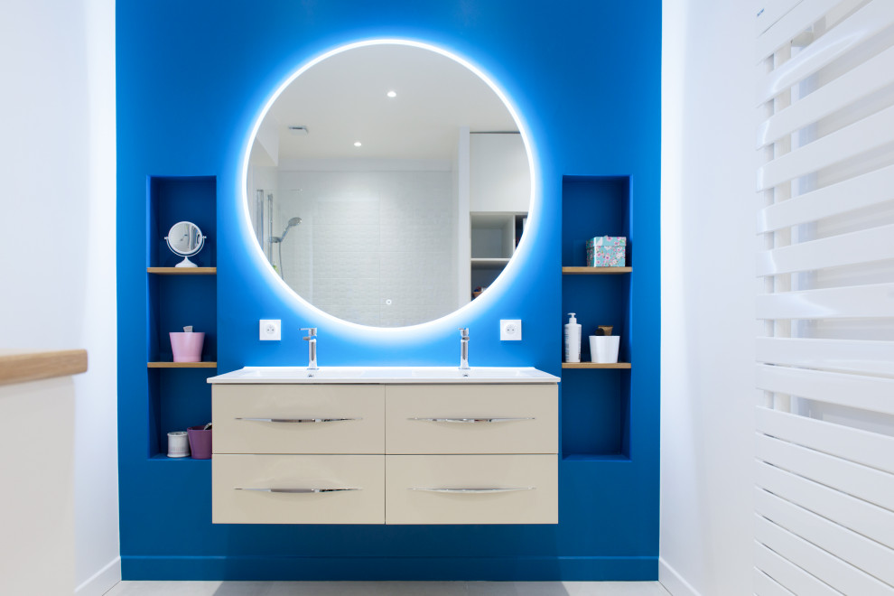 Exempel på ett stort modernt vit vitt badrum med dusch, med öppna hyllor, beige skåp, en kantlös dusch, vit kakel, keramikplattor, blå väggar, cementgolv, ett avlångt handfat, bänkskiva i akrylsten, beiget golv och med dusch som är öppen