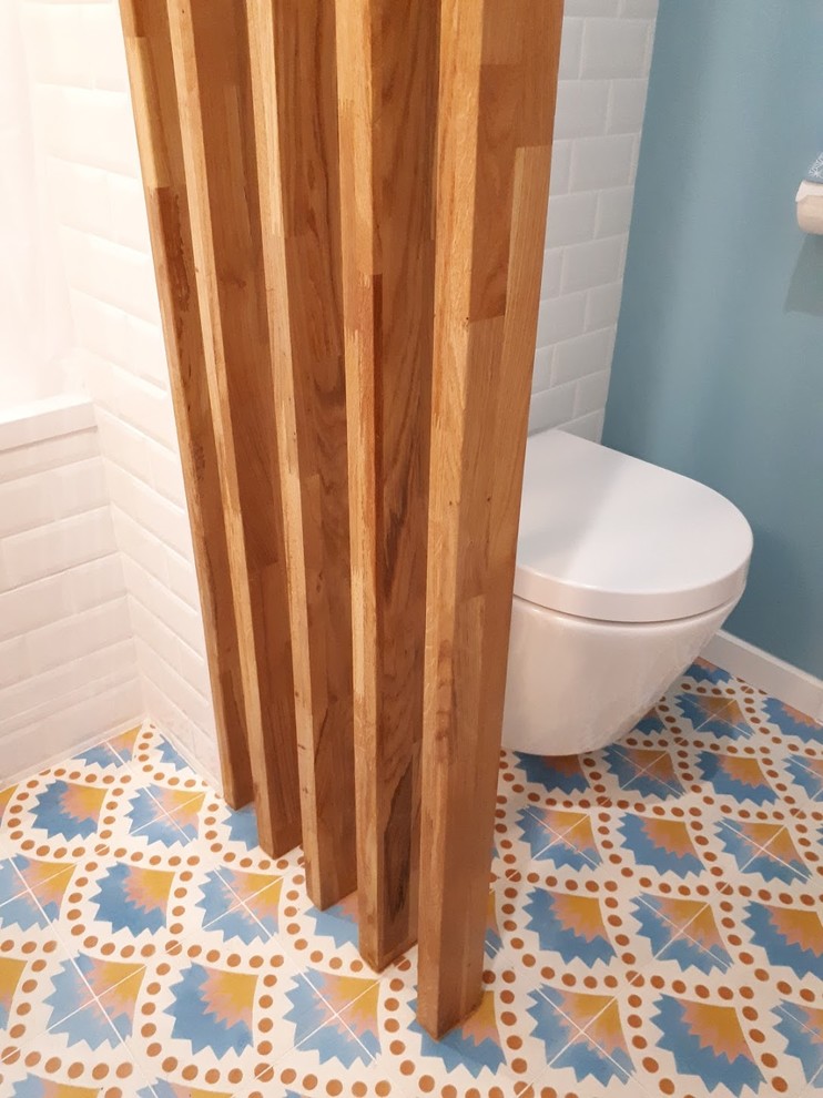 Inspiration pour une salle de bain principale design de taille moyenne avec une baignoire encastrée, WC suspendus, un carrelage blanc, un carrelage métro, un mur blanc, carreaux de ciment au sol, un lavabo posé, un plan de toilette en bois et un sol bleu.