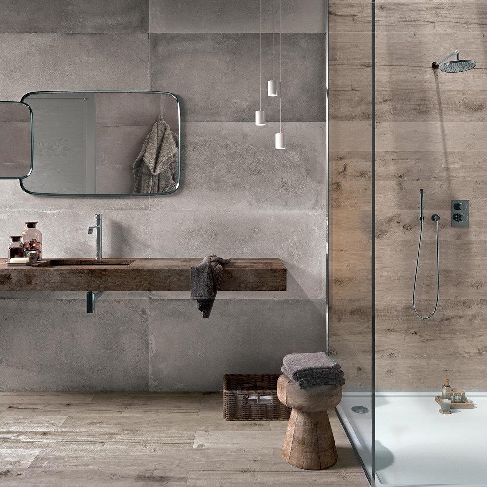 На фото: главная ванная комната в современном стиле с душем без бортиков, серой плиткой, цементной плиткой, серыми стенами, паркетным полом среднего тона, врезной раковиной, столешницей из дерева, открытым душем и коричневой столешницей