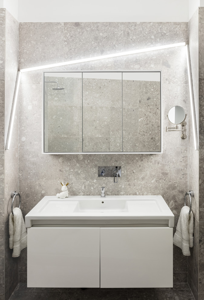 Пример оригинального дизайна: маленькая ванная комната в современном стиле с плоскими фасадами, белыми фасадами, монолитной раковиной, серой плиткой, серыми стенами и зеркалом с подсветкой для на участке и в саду