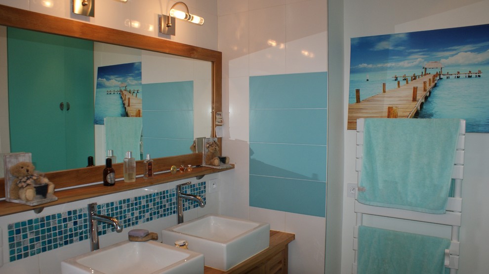 Exemple d'une salle de bain principale bord de mer de taille moyenne avec un placard à porte affleurante, des portes de placard beiges, une baignoire d'angle, une douche à l'italienne, un carrelage blanc, un carrelage bleu, des carreaux de béton, un mur blanc, parquet clair, une grande vasque, un plan de toilette en bois, un sol beige et une cabine de douche à porte battante.
