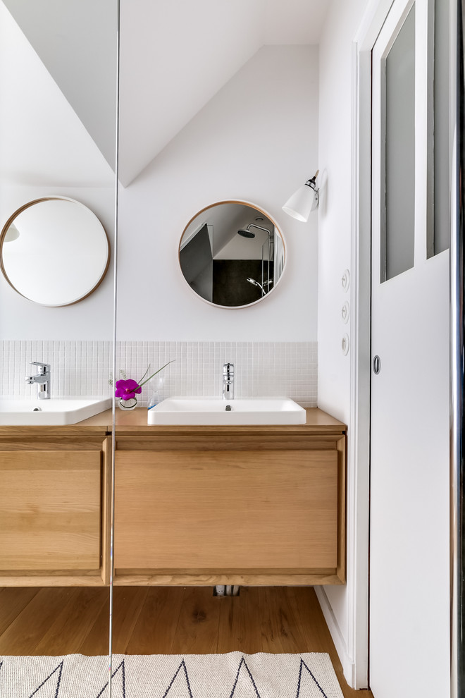 Réalisation d'une petite salle d'eau nordique en bois clair avec une douche à l'italienne, un carrelage beige, mosaïque, un mur blanc, une vasque, un sol en bois brun et un placard à porte plane.