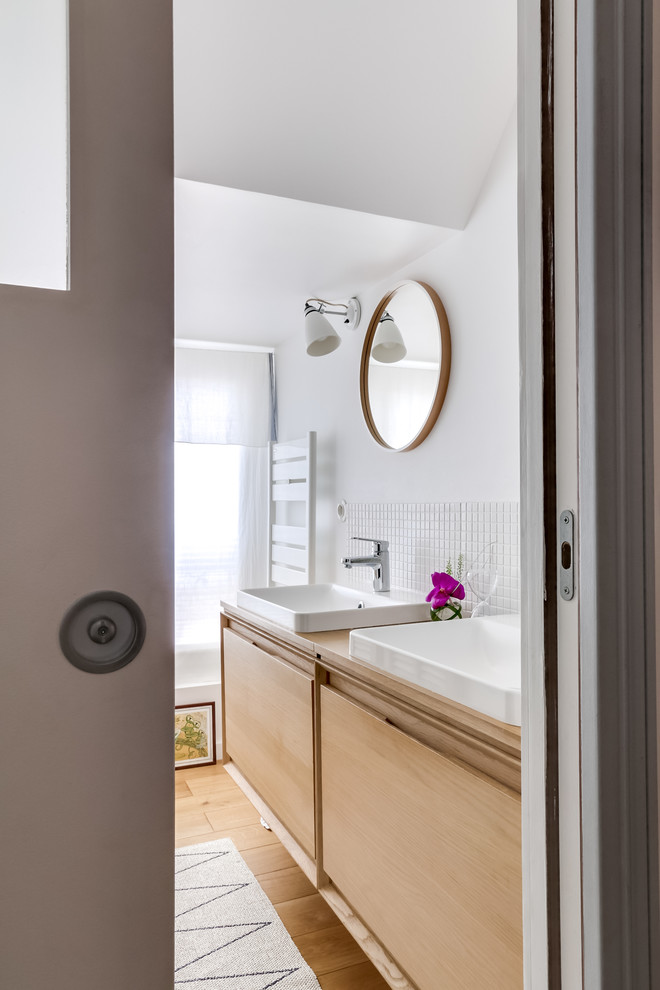 Nordisk inredning av ett litet badrum med dusch, med skåp i slitet trä, en kantlös dusch, beige kakel, mosaik, vita väggar, ett fristående handfat, mellanmörkt trägolv och släta luckor