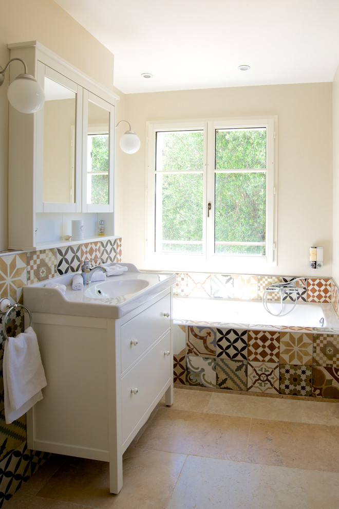Aménagement d'une salle de bain avec un placard à porte affleurante, des portes de placard beiges, une baignoire encastrée, un carrelage multicolore, des carreaux de béton, un mur beige, tomettes au sol, un plan vasque, un sol beige et un plan de toilette blanc.