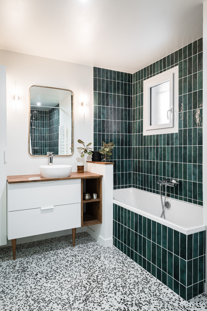 Corner bathtub - contemporary green tile and subway tile single-sink corner bathtub idea in Bordeaux with flat-panel cabinets, white cabinets, white walls, a vessel sink, wood countertops, brown countertops and a freestanding vanity