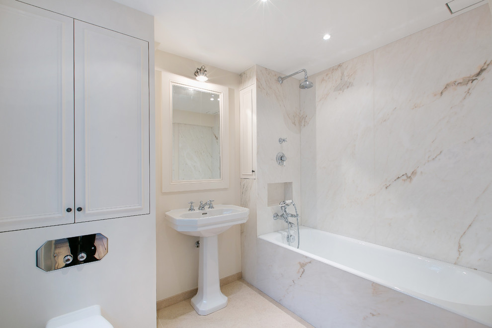Esempio di una stanza da bagno padronale chic di medie dimensioni con vasca da incasso, WC sospeso, lastra di pietra, pareti beige e lavabo a colonna
