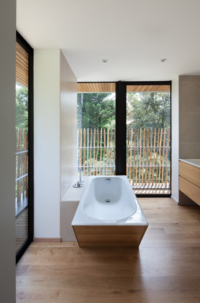 Foto de cuarto de baño principal contemporáneo de tamaño medio con bañera encastrada, paredes blancas, suelo de madera en tonos medios y lavabo bajoencimera