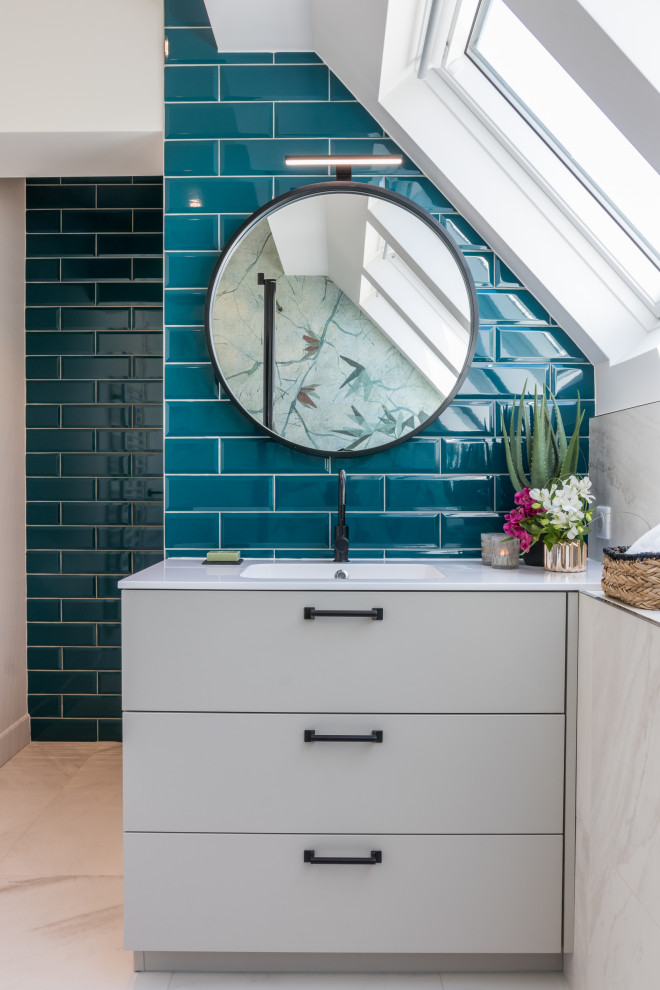 Idée de décoration pour une salle de bain design avec un placard à porte plane, des portes de placard grises, un carrelage bleu, un mur blanc, un lavabo intégré, un plan de toilette blanc, meuble simple vasque et meuble-lavabo encastré.