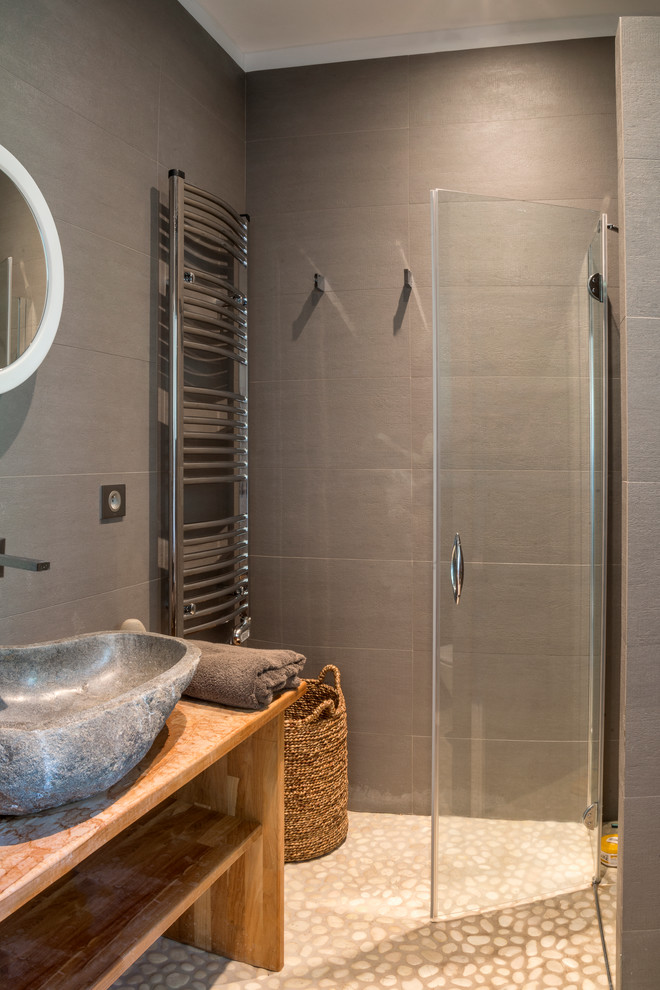 Exempel på ett modernt brun brunt badrum med dusch, med klinkergolv i småsten, öppna hyllor, skåp i mellenmörkt trä, en dusch i en alkov, grå kakel, keramikplattor, ett fristående handfat och träbänkskiva