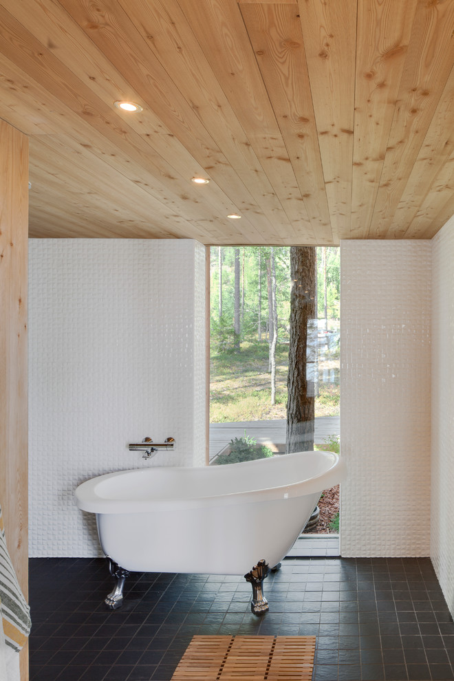 Cette photo montre une salle de bain principale scandinave de taille moyenne avec une baignoire sur pieds, un carrelage blanc, un mur blanc et un sol en ardoise.