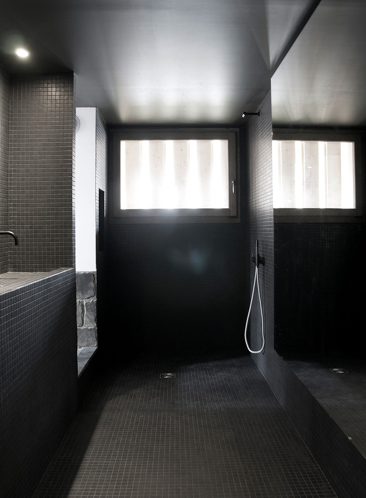 Inspiration för ett funkis badrum med dusch, med ett integrerad handfat, öppna hyllor, kaklad bänkskiva, ett undermonterat badkar, en kantlös dusch, svart kakel, keramikplattor, svarta väggar och mosaikgolv