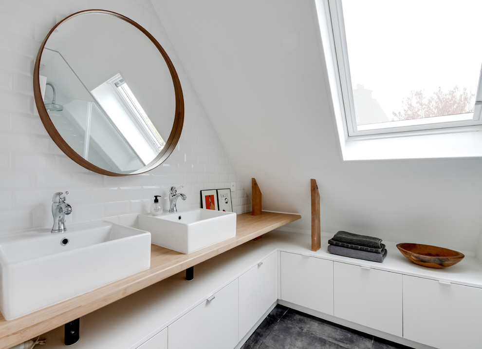 Cette photo montre une salle de bain principale tendance avec un placard à porte plane, des portes de placard blanches, un mur blanc, une vasque, un plan de toilette en bois et un plan de toilette beige.