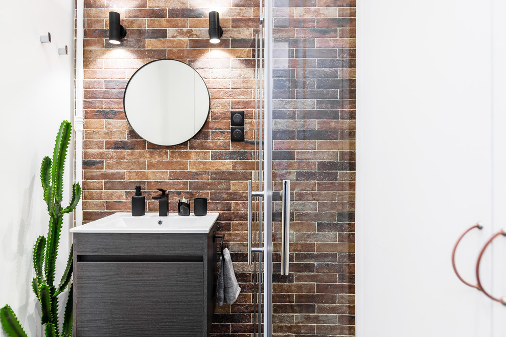 Inredning av ett industriellt litet vit vitt en-suite badrum, med släta luckor, grå skåp, en kantlös dusch, en vägghängd toalettstol, röd kakel, stenkakel, röda väggar, klinkergolv i keramik, ett konsol handfat, bänkskiva i akrylsten, svart golv och dusch med gångjärnsdörr