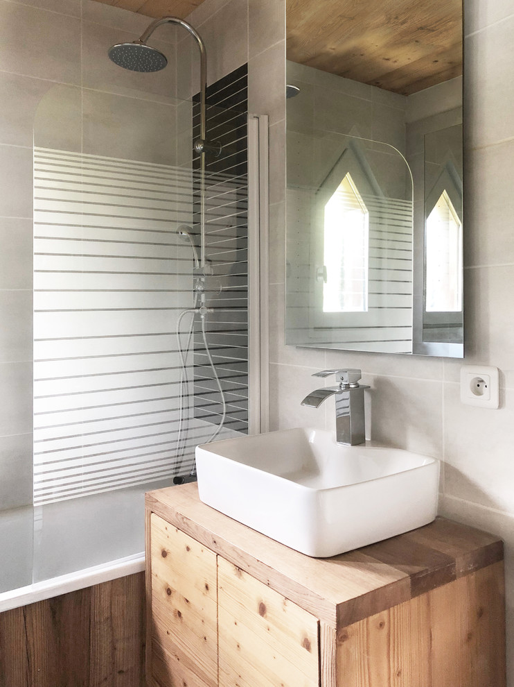 Imagen de cuarto de baño rústico con puertas de armario de madera en tonos medios, baldosas y/o azulejos grises y lavabo encastrado
