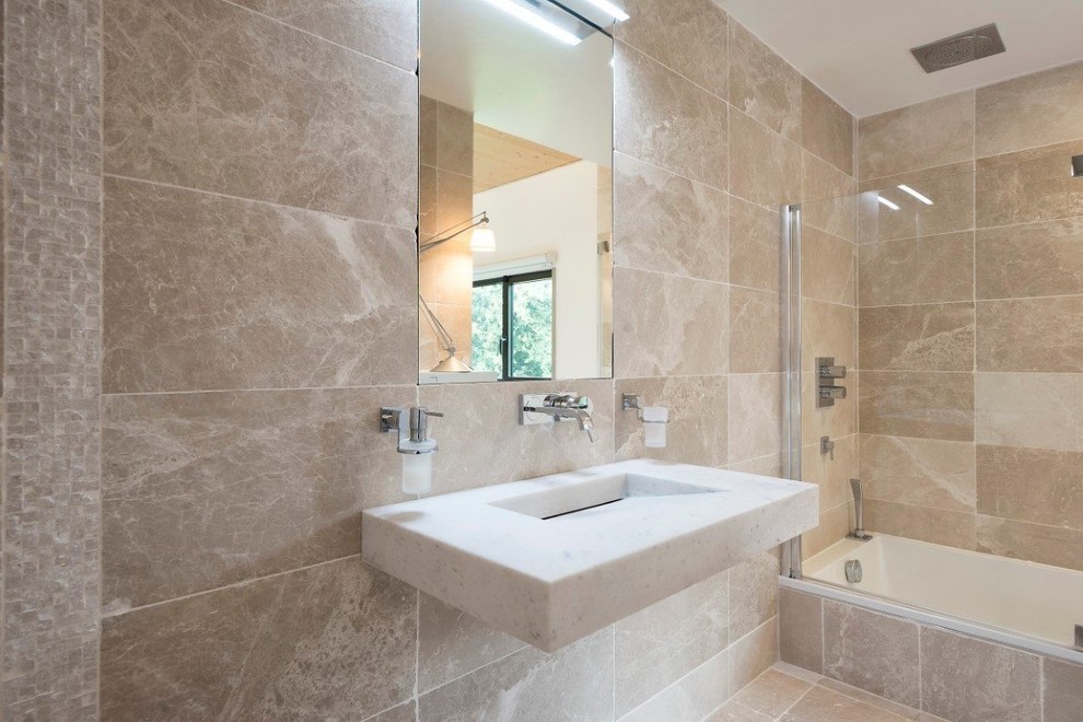 Modern inredning av ett litet beige beige en-suite badrum, med en dusch/badkar-kombination, beige kakel, luckor med profilerade fronter, beige skåp, ett undermonterat badkar, marmorkakel, beige väggar, marmorgolv, ett väggmonterat handfat, granitbänkskiva, beiget golv och dusch med gångjärnsdörr
