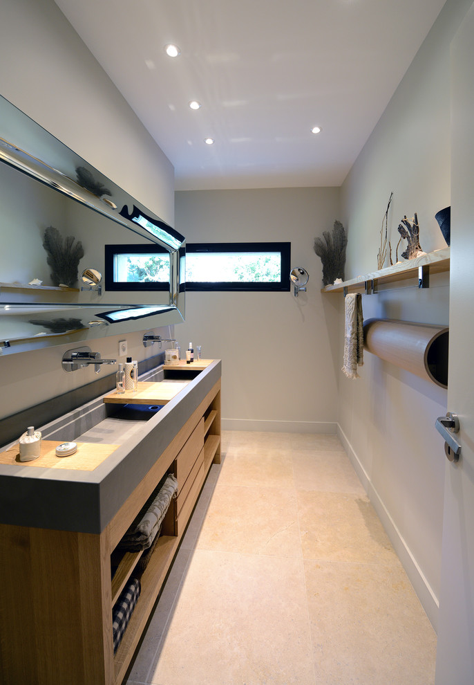 Cette image montre une salle d'eau minimaliste en bois clair de taille moyenne avec un placard à porte plane, un sol en carrelage de céramique, un plan vasque, un plan de toilette en surface solide et un sol beige.
