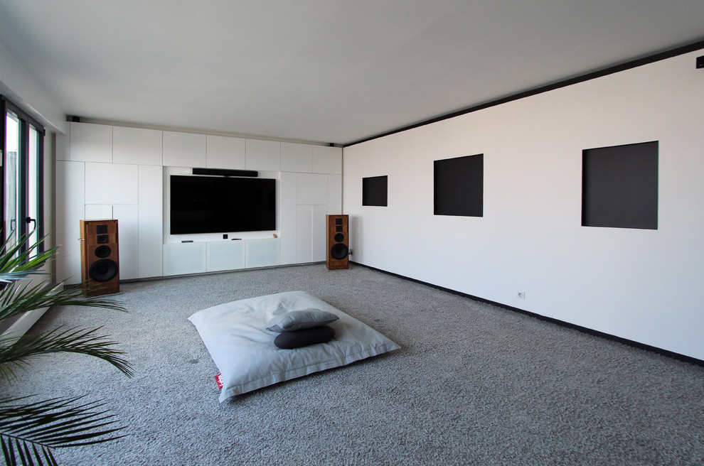 Modelo de cine en casa cerrado actual grande con paredes blancas, moqueta, televisor colgado en la pared y suelo gris
