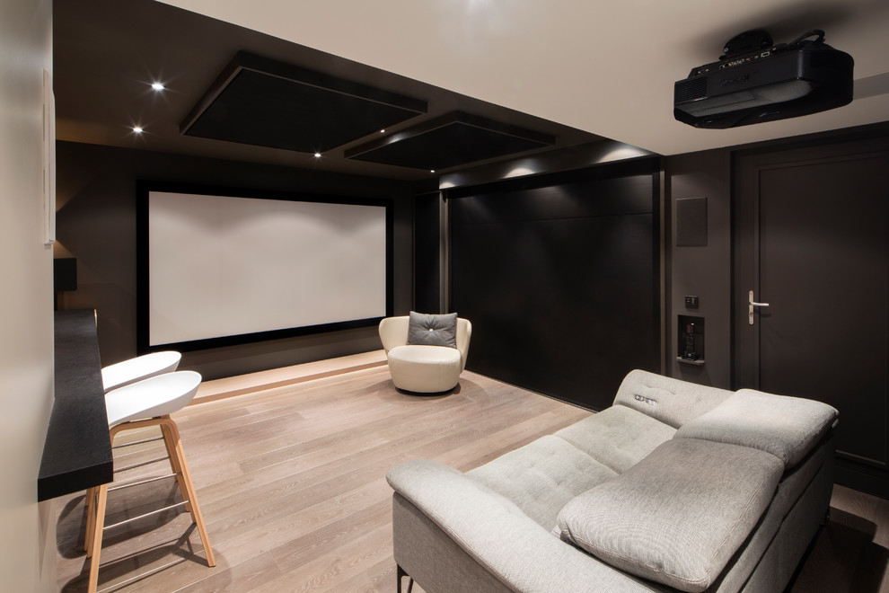 Idée de décoration pour une petite salle de cinéma design fermée avec un mur gris, un sol en bois brun et un écran de projection.