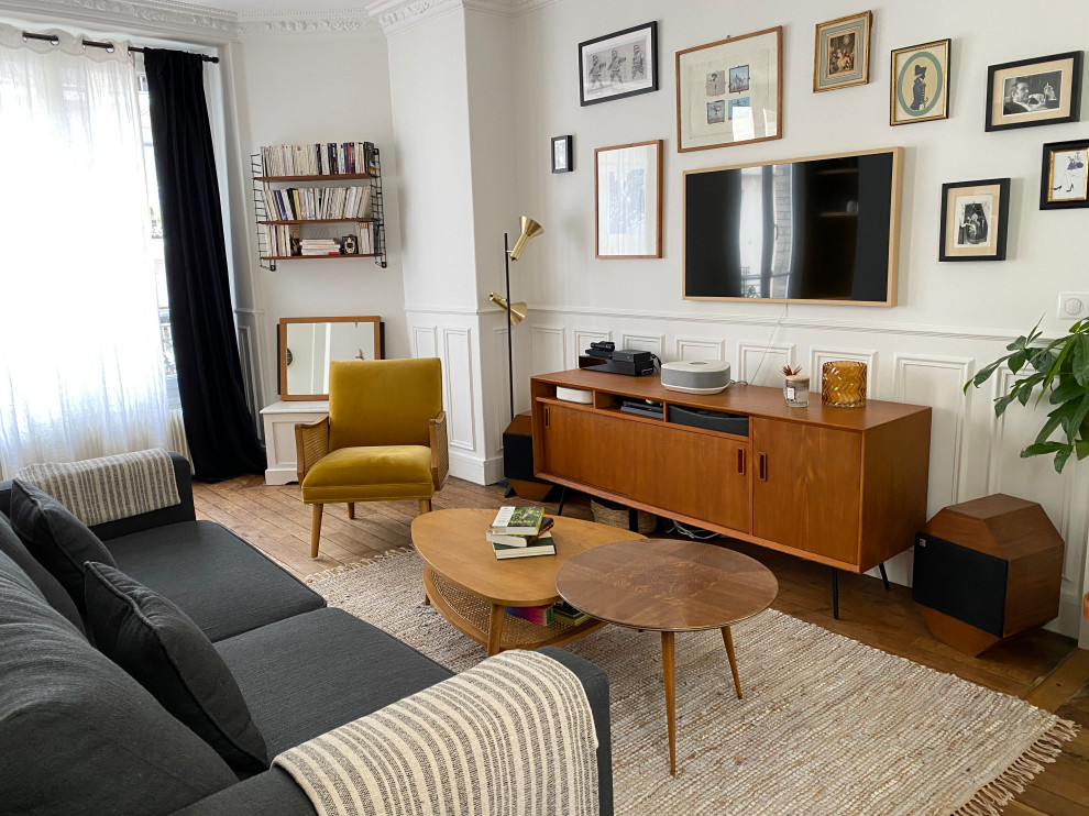 Cette image montre une salle de séjour vintage de taille moyenne et ouverte avec un mur blanc, un sol en bois brun, un téléviseur dissimulé et boiseries.