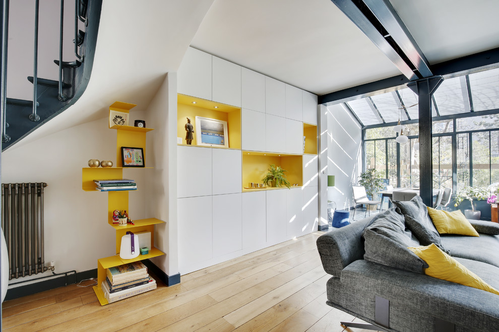 Cette image montre une petite salle de séjour design avec aucun téléviseur, un mur blanc, parquet clair, aucune cheminée et un sol marron.