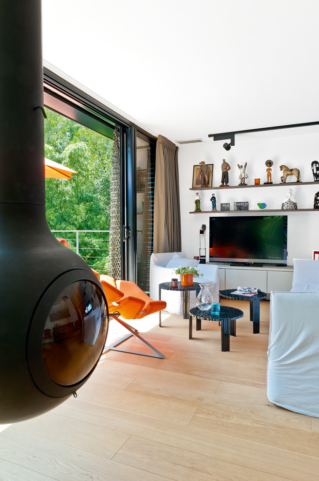Bild på ett mellanstort funkis allrum med öppen planlösning, med vita väggar, ljust trägolv och en fristående TV