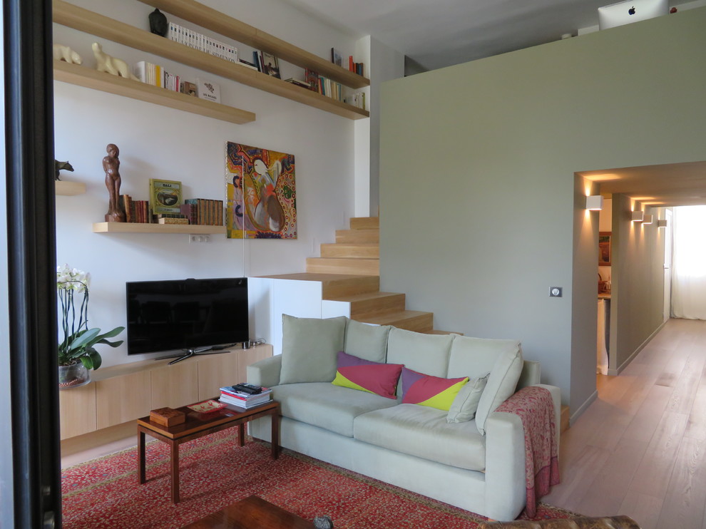 Imagen de sala de estar con biblioteca clásica pequeña sin chimenea con paredes blancas, suelo de madera clara y televisor independiente