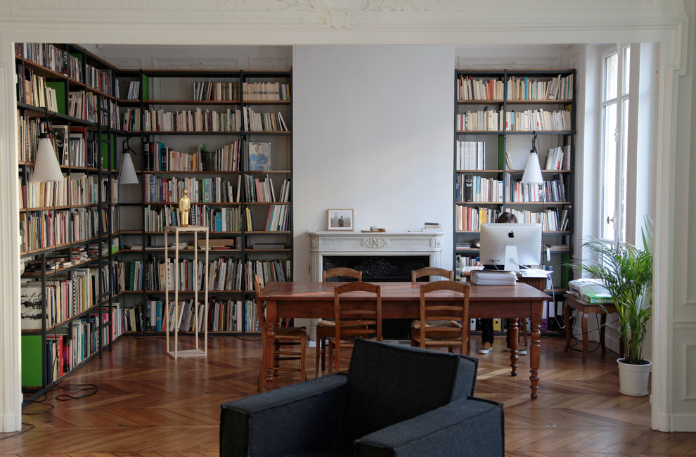 Modelo de despacho contemporáneo de tamaño medio con biblioteca, suelo de madera en tonos medios y todas las chimeneas
