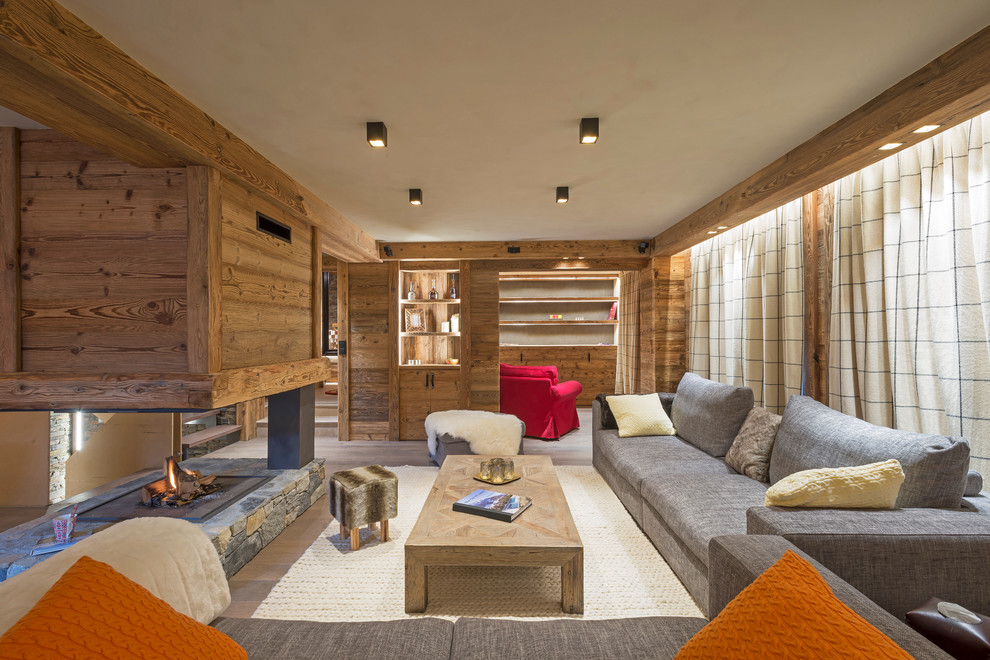Immagine di un grande soggiorno stile rurale aperto con pareti marroni, pavimento in legno massello medio, camino bifacciale, cornice del camino in legno e nessuna TV