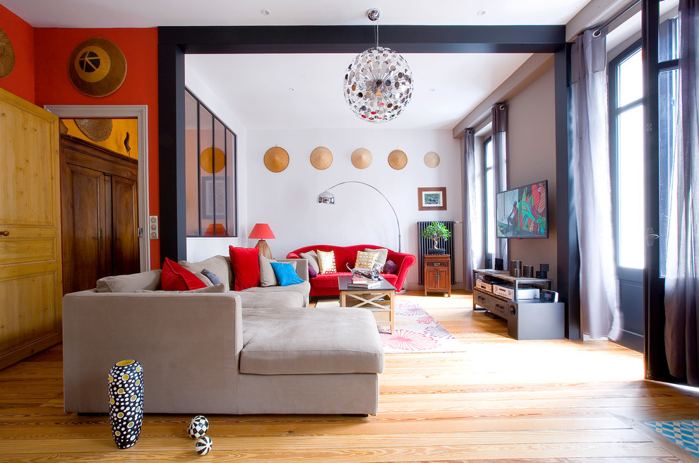 Imagen de sala de estar ecléctica con suelo de madera en tonos medios y televisor colgado en la pared