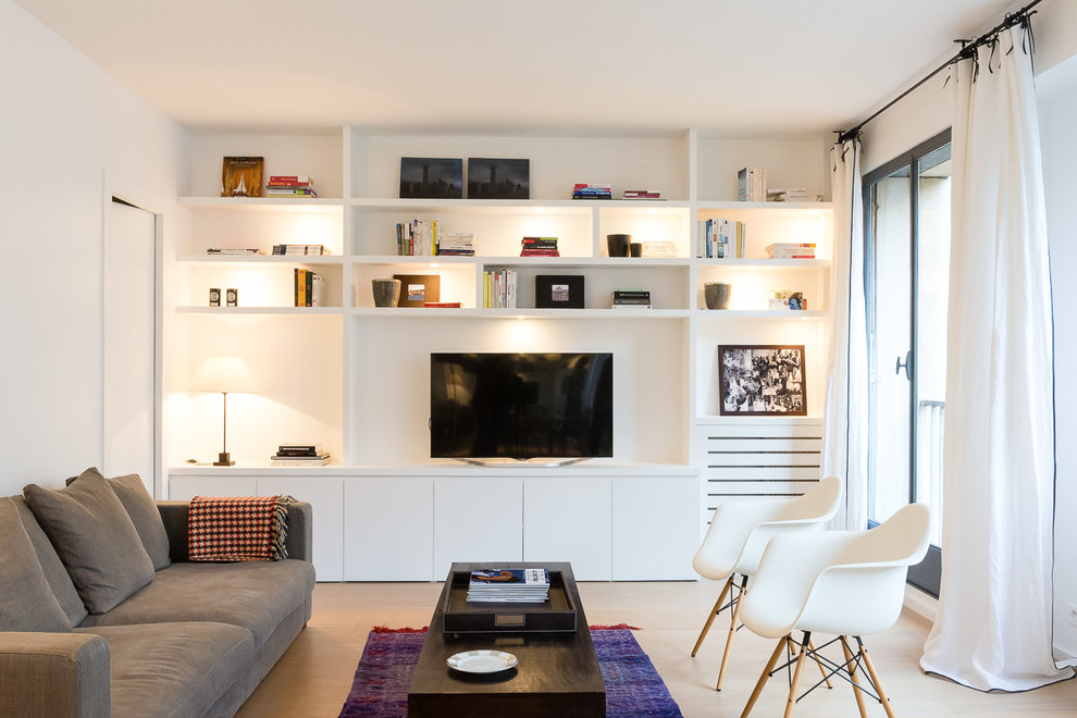 На фото: гостиная комната среднего размера в современном стиле с белыми стенами, светлым паркетным полом, телевизором на стене и ковром на полу