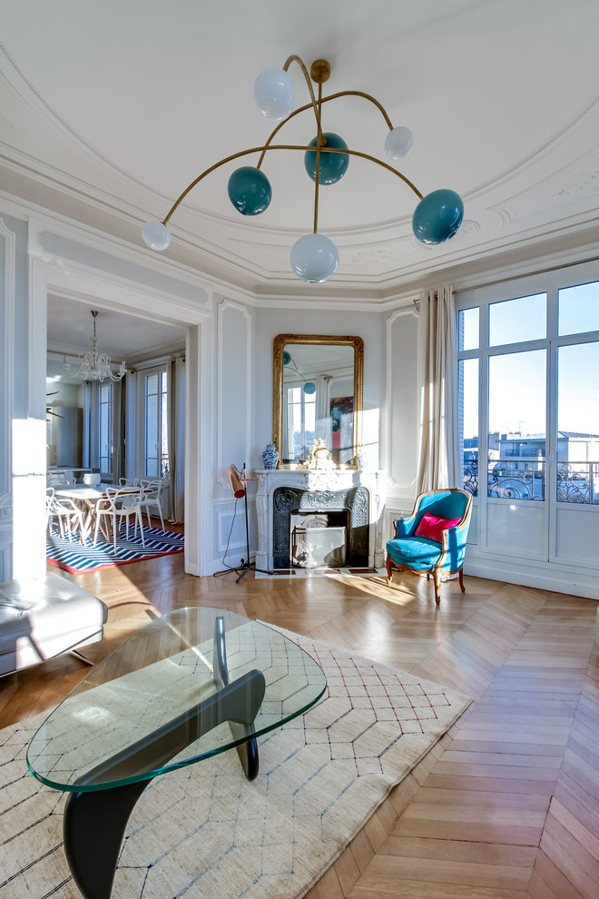 Großes, Offenes Klassisches Wohnzimmer mit grauer Wandfarbe, hellem Holzboden, Eckkamin, Kaminumrandung aus Stein und freistehendem TV in Paris