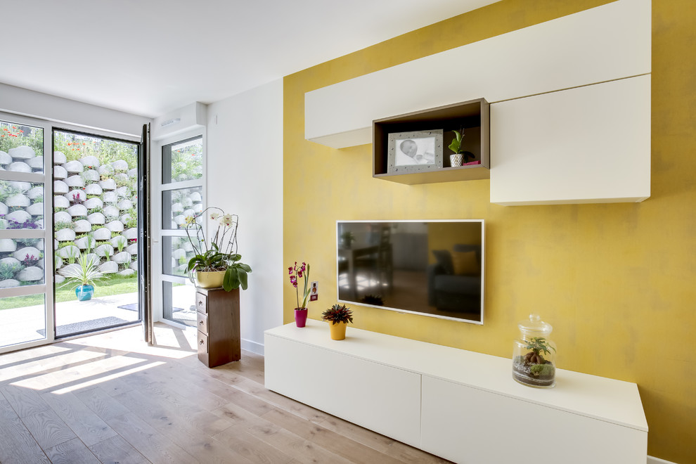 Aménagement d'une petite salle de séjour contemporaine ouverte avec un mur jaune, parquet clair, un téléviseur fixé au mur, un sol marron et aucune cheminée.