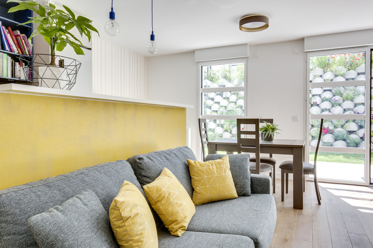 Свежая идея для дизайна: маленькая открытая гостиная комната в современном стиле с желтыми стенами, светлым паркетным полом, телевизором на стене и коричневым полом без камина для на участке и в саду - отличное фото интерьера
