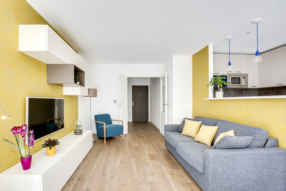 На фото: маленькая открытая гостиная комната в современном стиле с светлым паркетным полом, телевизором на стене, коричневым полом и желтыми стенами без камина для на участке и в саду с