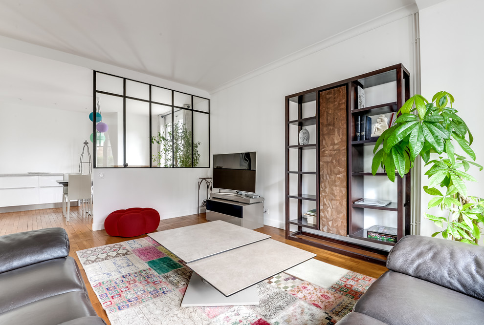 Cette image montre une grande salle de séjour design ouverte avec un mur blanc, un téléviseur indépendant, un sol en bois brun et aucune cheminée.