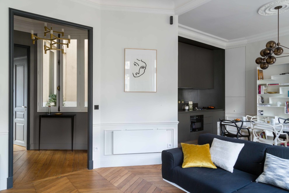 Стильный дизайн: открытая гостиная комната среднего размера в современном стиле с белыми стенами, светлым паркетным полом, стандартным камином, фасадом камина из камня, телевизором на стене и коричневым полом - последний тренд