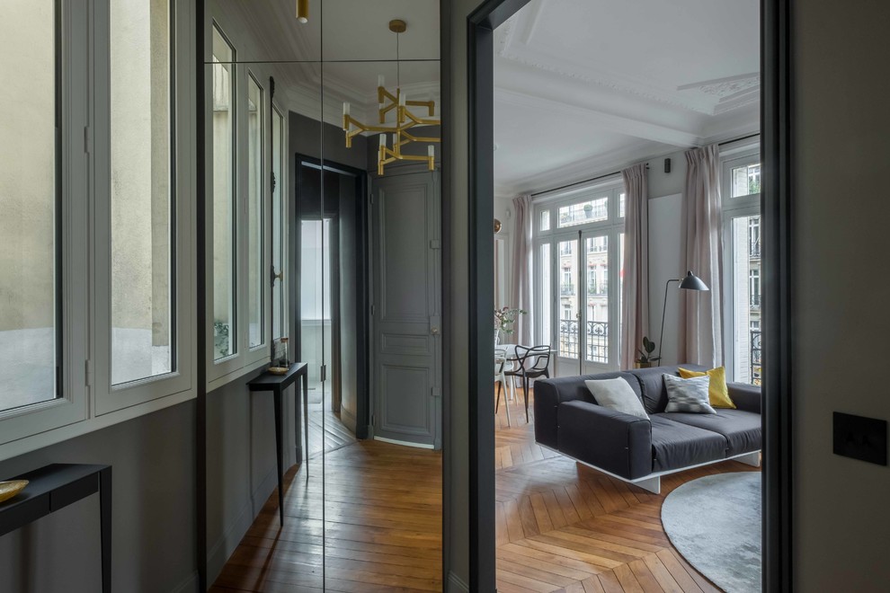Immagine di un piccolo soggiorno design con pareti grigie, parquet chiaro e pavimento marrone