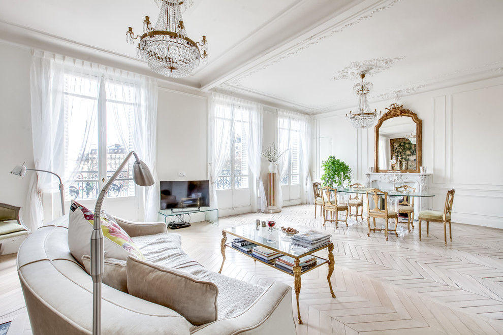 Modelo de sala de estar abierta tradicional renovada grande con paredes blancas, suelo de madera clara, todas las chimeneas, marco de chimenea de piedra y suelo blanco