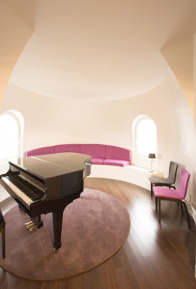 Cette image montre une salle de séjour design de taille moyenne et fermée avec une salle de musique, un mur blanc, un sol en bois brun et aucun téléviseur.