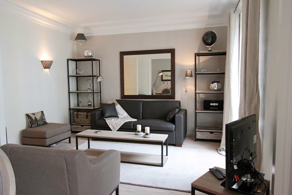 Cette photo montre une grande salle de séjour chic ouverte avec un bar de salon, un mur gris, parquet clair, un téléviseur indépendant et un sol beige.