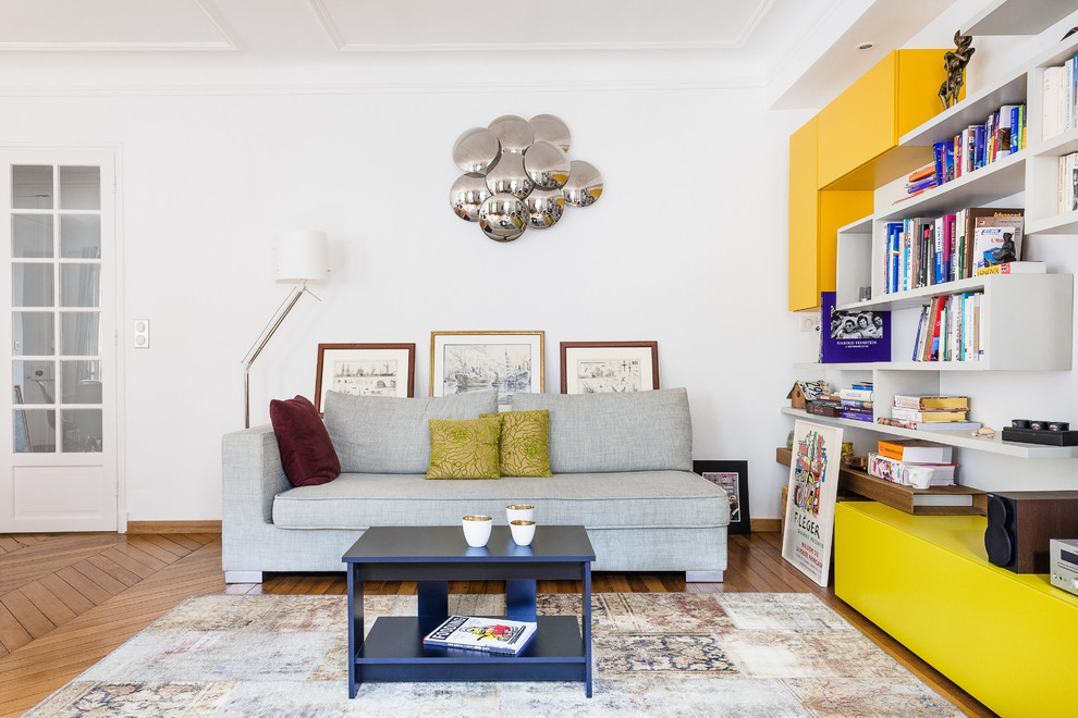 Foto de sala de estar con biblioteca abierta contemporánea de tamaño medio sin chimenea y televisor con paredes blancas y suelo de madera en tonos medios