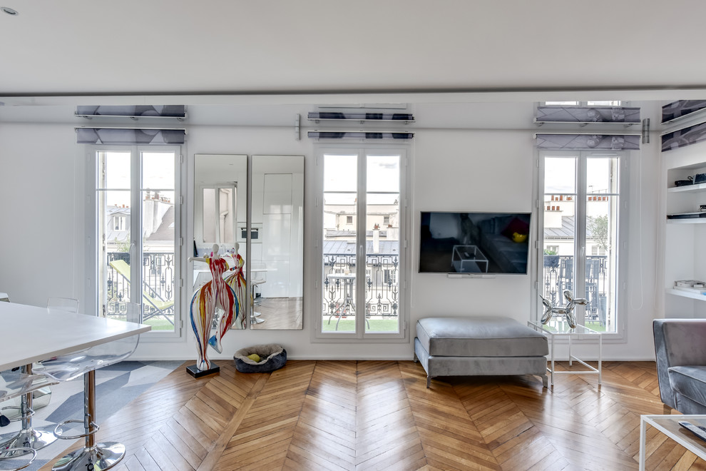 Foto di un soggiorno minimal di medie dimensioni e aperto con pareti bianche, parquet chiaro, TV a parete e pavimento beige